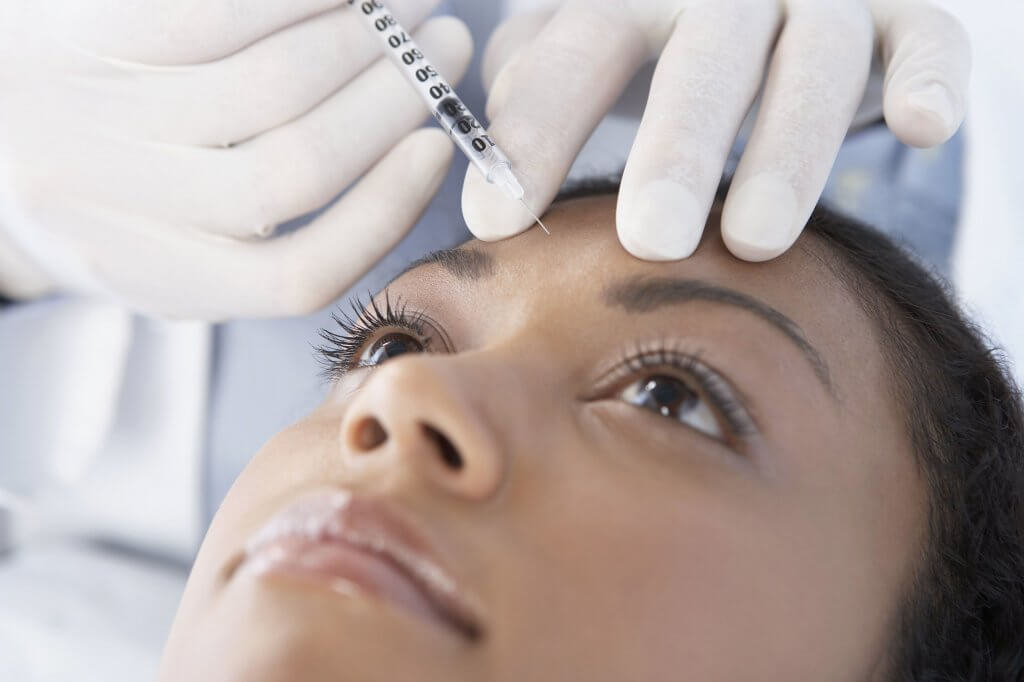 mulher aplicando toxina botulínica entre as sombrancelhas